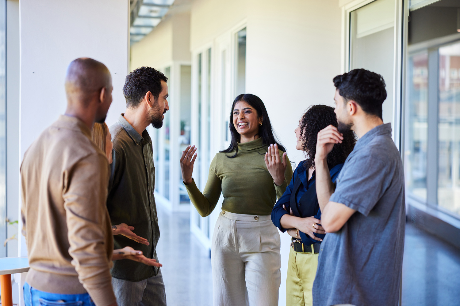 Diverse web design and development team discussing in office hallway.
