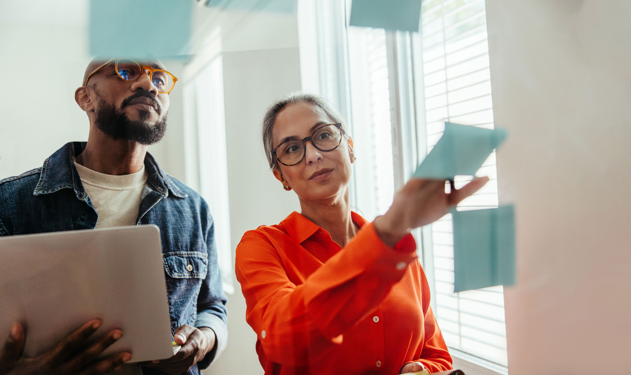 A man and woman work on website strategy using several sticky-notes.
